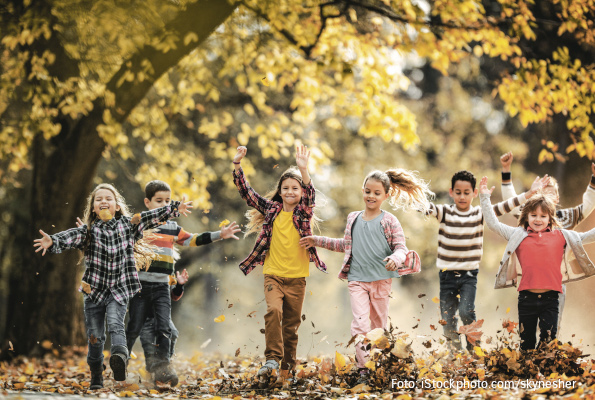 Kinder laufen durch bunten Herbstlaub